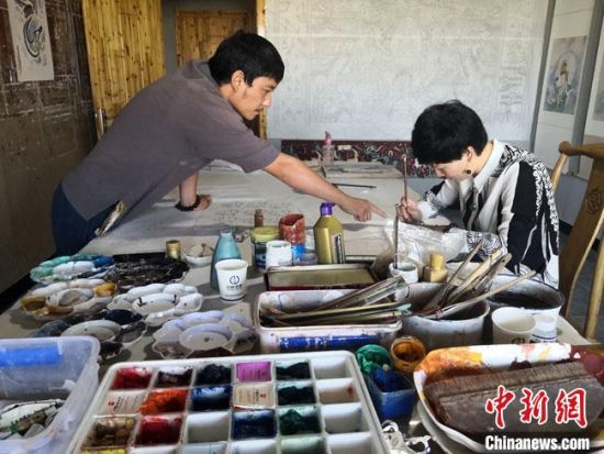 圖為2020年8月下旬，敦煌“80后”畫家張杰龍(左)在為云南麗江“學(xué)生”莫北講解敦煌壁畫的繪畫技巧?！●T志軍 攝