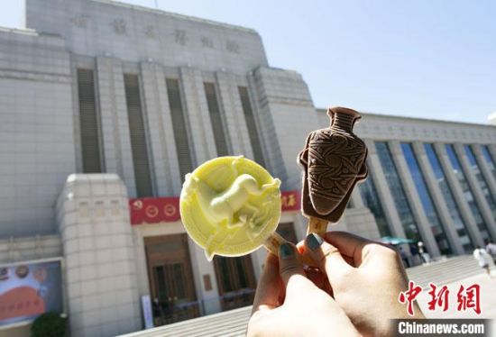 2021年7月30日，游客手拿“銅奔馬”“彩陶瓶”造型的雪糕，在甘肅省博物館前拍照打卡?！「哒?攝