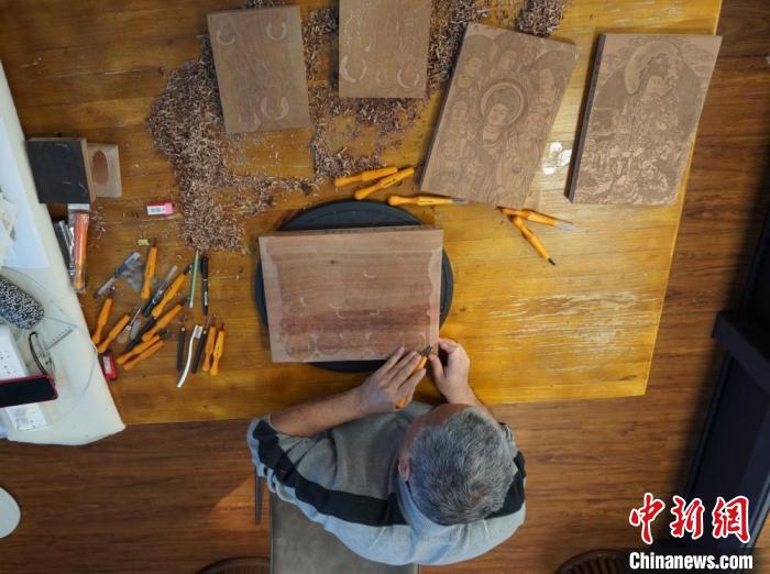 圖為徐晉林正在梨木木板上雕刻敦煌壁畫(huà)?！【琶赖┰?　攝