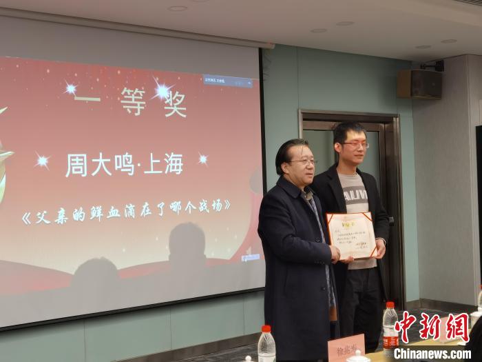 圖為作家、西北師范大學(xué)新聞與傳媒學(xué)院院長徐兆壽頒發(fā)一等獎證書，代領(lǐng)獎?wù)呱吓_領(lǐng)獎?！钅?攝