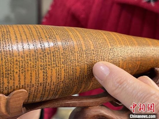 圖為長(zhǎng)約二十公分的長(zhǎng)條葫蘆雕刻佛教經(jīng)文作品。　張婧 攝