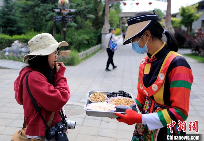 圖為身穿土族服飾的女性介紹當(dāng)?shù)靥厣〕??！⊙Φ?攝
