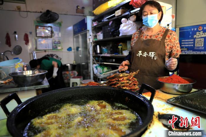 圖為平安驛·河湟民俗文化體驗地內(nèi)的商戶炸干板魚?！⊙Φ?攝