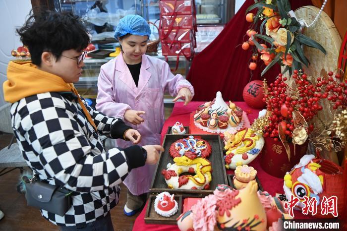 1月25日，隨著春節(jié)臨近，蘭州一花饃店“龍”元素花饃熱銷。圖為工作人員向顧客推薦“龍”元素花饃。九美旦增 攝</p><p>