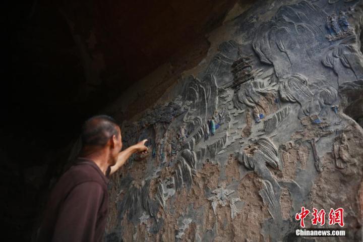 7月15日，甘肅省平?jīng)鍪袥艽h百里石窟長廊羅漢洞石窟內(nèi)，該窟文保員郭建平介紹窟內(nèi)石刻彩繪壁畫。郭建平家中三代人曾自發(fā)保護(hù)羅漢洞石窟。羅漢洞石窟遺存40余個(gè)窟龕，以北魏至清代風(fēng)格為主。中新社記者 李亞龍 攝