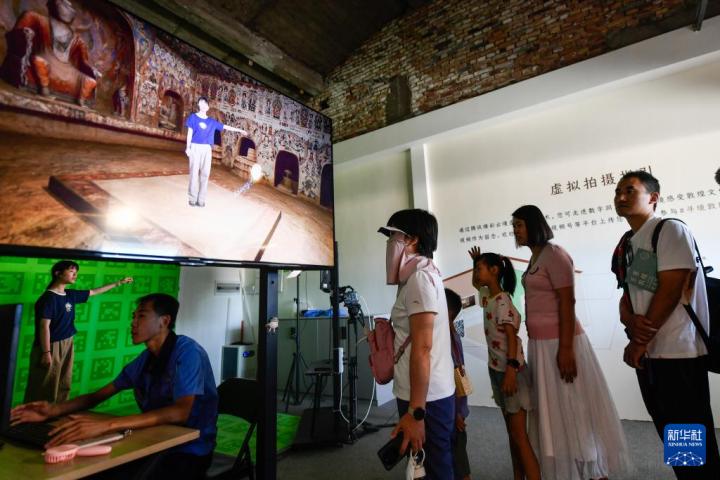 7月22日，游客體驗“尋境敦煌——數(shù)字敦煌沉浸展”后，在虛擬演播廳拍攝一段真人與洞窟虛擬場景交互的視頻。新華社記者 郎兵兵 攝</p>
<p>