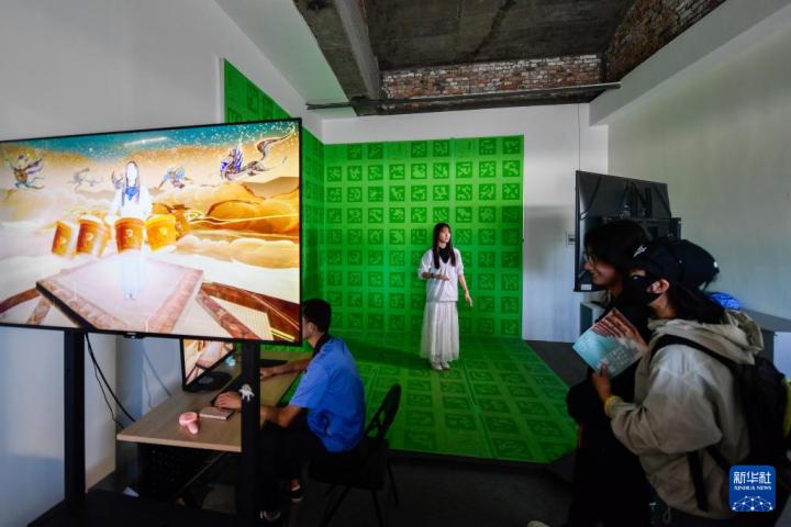 7月22日，游客體驗“尋境敦煌——數(shù)字敦煌沉浸展”后，在虛擬演播廳拍攝一段真人與洞窟虛擬場景交互的視頻。新華社記者 郎兵兵 攝</p>
<p>